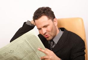 man reading poor financial results in newspaper